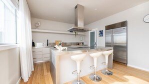 A modern kitchen with a central island, stainless steel appliances, and a bar area with stools.