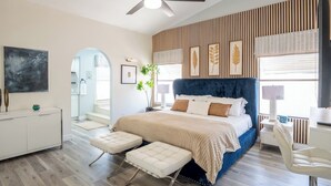 Ein Schlafzimmer mit einem Bett, einem Schreibtisch, einem Stuhl, einem Deckenventilator und einem Fenster.