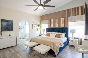 Ein Schlafzimmer mit einem Bett, einem Schreibtisch, einem Stuhl, einem Deckenventilator und einem Fenster.