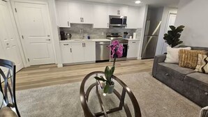 Una cocina moderna con armarios blancos, electrodomésticos de acero inoxidable y una isla central con una planta en maceta.