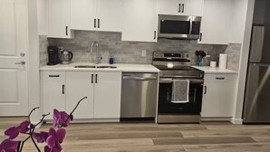 Una cocina moderna con armarios blancos, electrodomésticos de acero inoxidable y un salpicadero de azulejos.