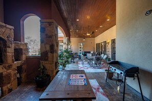 A covered patio with stone walls, a grill, and a table with a menu. - 
Unique Multi-Family Getaway with Pool, Game room, Theater & 6 Themed Bedrooms (Spring Branch)