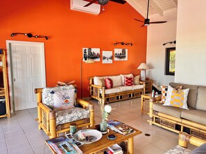 A room with a white door, a sofa set, a coffee table with magazines, and a wall with pictures. - The Serene Getaway  - Chic Private Room & Bath Near Grace Bay (Providenciales)