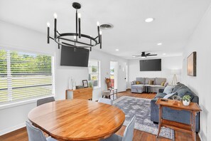 A modern living room with a dining table, sofa, and a chandelier. - The Staytion (College Station)
