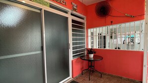 A room with a red wall, a ceiling fan, a window with a view, and a door with frosted glass. - Your tropical escape in Playa Santa, Guanica. Beach days starts here. (Guánica)