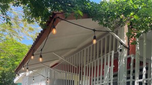 A covered outdoor area with a metal fence, a cart, and a building with a red and white color scheme. - Your tropical escape in Playa Santa, Guanica. Beach days starts here. (Guánica)