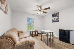 A compact living space with a ceiling fan, a small table with chairs, a sofa, a refrigerator, and a door. - Private 1-Bedroom with Private Entrance Ocala, FL (Ocala)