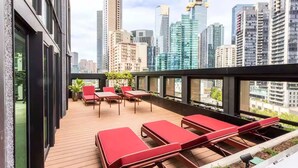 Eine Dachterrasse mit Liegestühlen, einem kleinen Tisch und Topfpflanzen.