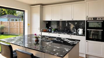 A modern kitchen with a central island, stainless steel appliances, and a view of the backyard.