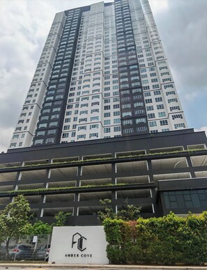 A high-rise building with multiple floors, a sign reading 'AMBER COVE,' and a parking structure with greenery. - 7 Pax 2 Bedroom Netflix Wi-Fi Melaka Seaview (Melaka)