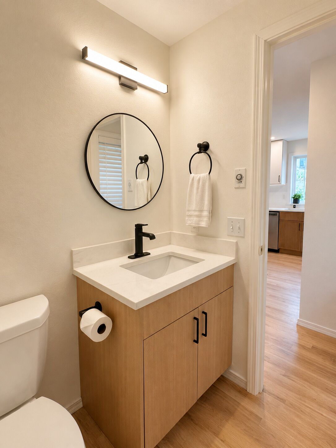 Une salle de bain moderne équipée de toilettes, d’un lavabo, d’un miroir, d’un porte-serviettes et d’un porte-rouleau de papier toilette.