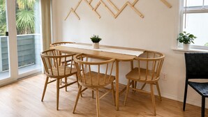 A dining area with a wooden table and chairs, a potted plant, and a wall-mounted wooden art piece. - Central Ballard Townhome / Sleeps 8 / Direct Bus Line to Stadium (Seattle)