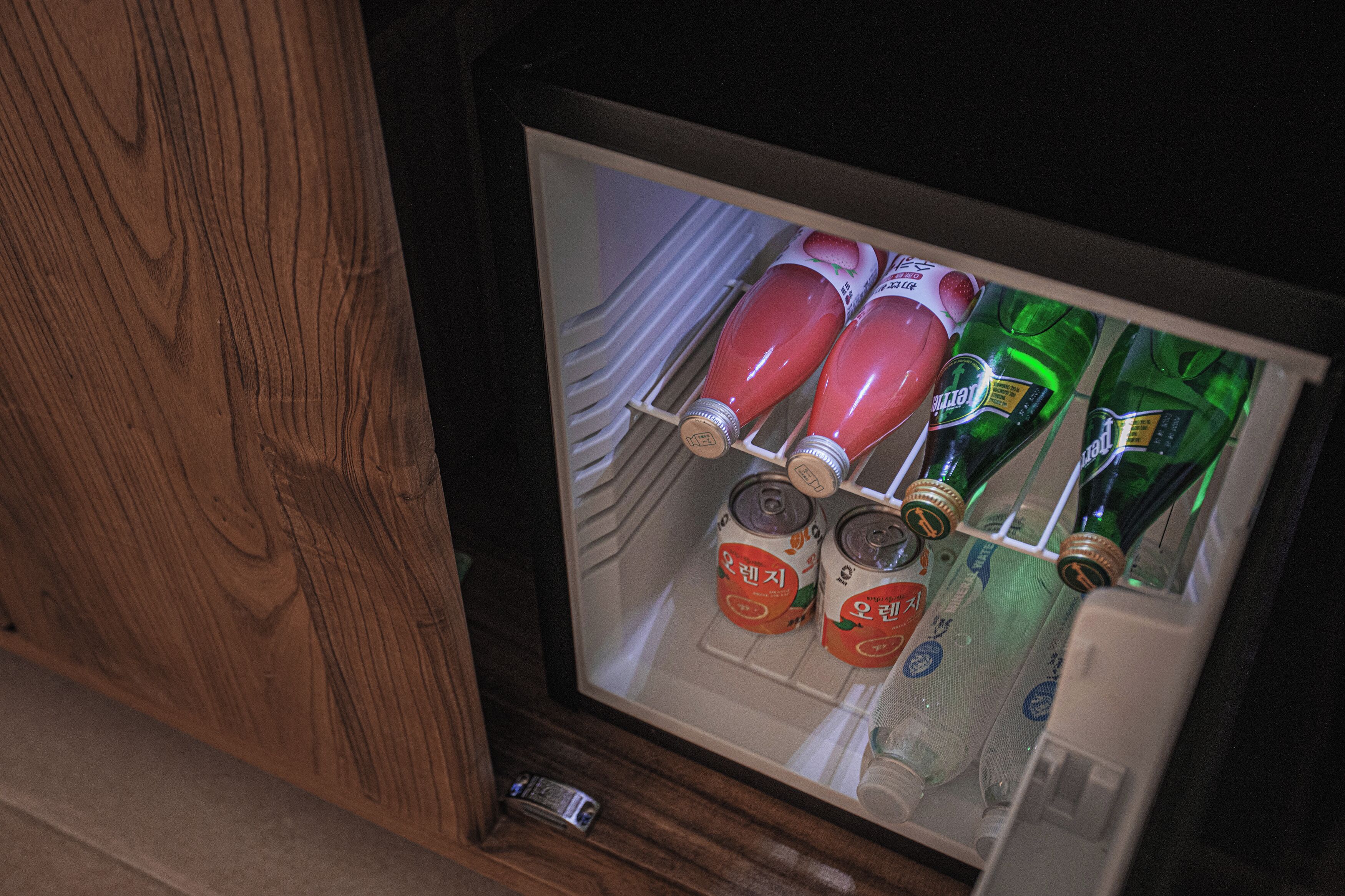Un refrigerador con bebidas y una botella pequeña.