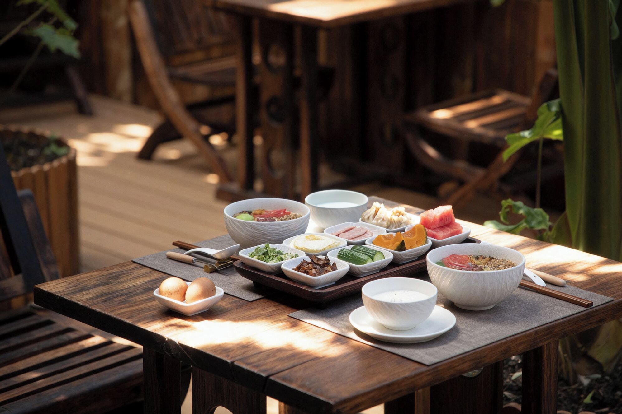 A wooden table with various dishes and bowls, likely a meal setting.