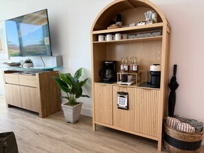 A hotel room with a wooden cabinet, a coffee machine, and a sign indicating a dry cleaning service. - {SURF INN} Pacific Beach-La Jolla area Beach Haus with Modern Designer Vibes (San Diego)