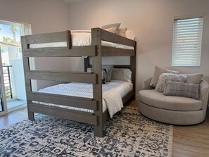 A bunk bed with a wooden frame, a patterned rug, and a round armchair with cushions. - {SURF INN} Pacific Beach-La Jolla area Beach Haus with Modern Designer Vibes (San Diego)