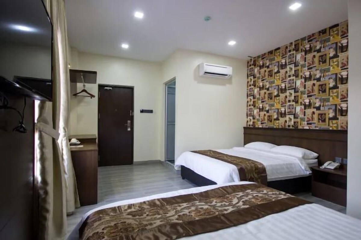 A hotel room with two beds, a wardrobe, a mirror, an air conditioning unit, and a wall decorated with photos.