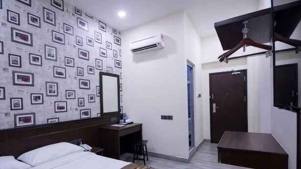 A hotel room with a bed, desk, wardrobe, and an air conditioning unit. - Islander Lodge by LWE (George Town)