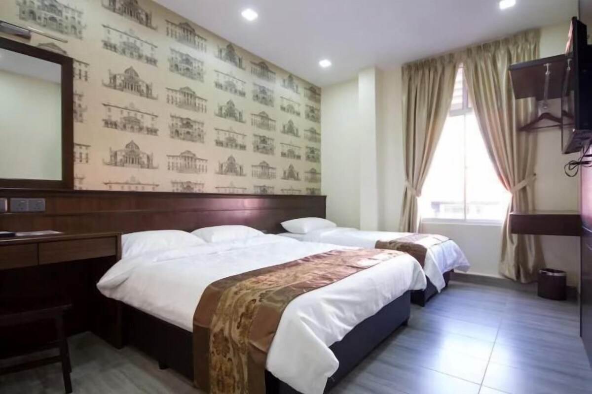 A hotel room with two beds, a desk, a mirror, and a window with curtains.