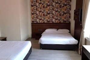 A hotel room with a large bed, a bedside table, and a wall covered with photos. - Islander Lodge by LWE (George Town)