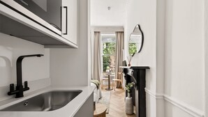 A modern kitchen with a sink, cabinets, and a fireplace. - GuestReady - Modern Double En-Suite near Euston (London)