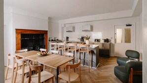 A modern kitchen with a central island, wooden dining table, and chairs. - GuestReady - Modern Double En-Suite near Euston (London)