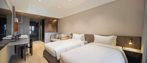 Quarto de hotel com duas camas, uma escrivaninha e uma cadeira.