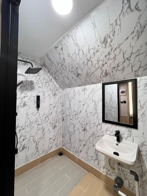 A bathroom with a marble wall, a sink, and a mirror. - Paragon Nagoya Hotel Batam (Batam)