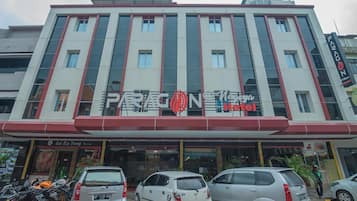 Un hotel con facciata rossa e bianca, diverse finestre e un logo ben visibile.