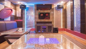 A modern interior with a glass coffee table, leather seating, a fireplace, and wall-mounted speakers. - Paragon Nagoya Hotel Batam (Batam)