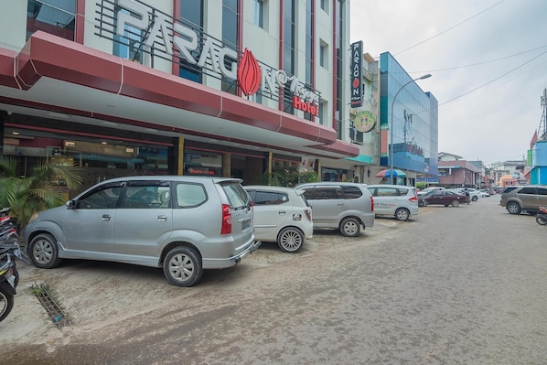 A hotel with a red and white facade, parked cars, and a street view.