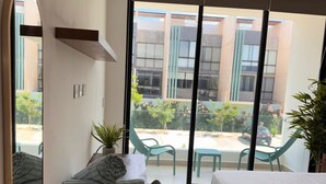 Ein Hotelzimmer mit Bett, Schreibtisch mit Stuhl, Spiegel und Blick ins Freie.