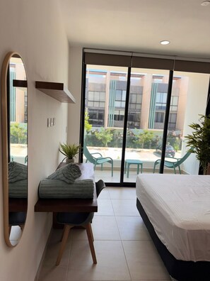 Ein Hotelzimmer mit Bett, Schreibtisch mit Stuhl, Spiegel und Blick ins Freie.
