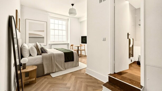 Ein modernes Schlafzimmer mit Bett, Nachttisch und Blick ins Bad.