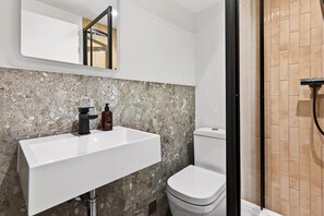 A bathroom with a white sink, a toilet, and a shower area. - GuestReady - Modern Double En-Suite in Bloomsbury (London)
