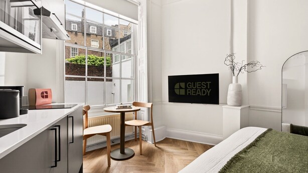 Een moderne keuken met een eethoek, een bed en een bordje met de tekst 'GUEST READY'.