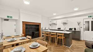 Una cocina moderna con una isla central, sillas de madera y una mesa de comedor con platos.