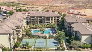 Un hôtel à plusieurs étages doté d’une piscine, de courts de tennis et d’un jardin aménagé.