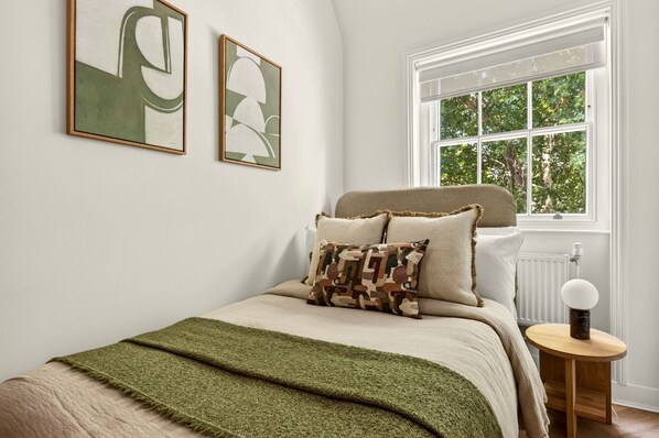 A bedroom with a bed, a window, and two framed artworks on the wall. - GuestReady - Modern Double Room near King's Cross (London)
