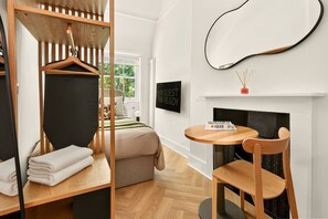 A modern room with a bunk bed, a round wooden table, a chair, a fireplace, and a TV displaying 'GUEST READY'. - GuestReady - Modern Double Room near King's Cross (London)
