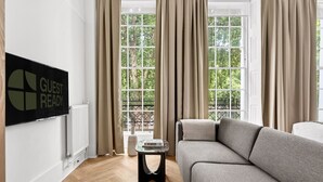 Een moderne woonkamer met een bank, een televisie en een raam met gordijnen.