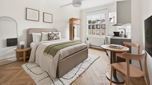 Un dormitorio moderno con cama, mesitas de noche, una ventana con vistas, una mesa redonda y una silla.