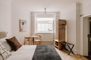 Ein Schlafzimmer mit Bett, Schreibtisch, Stuhl, Heizkörper und Fenster.