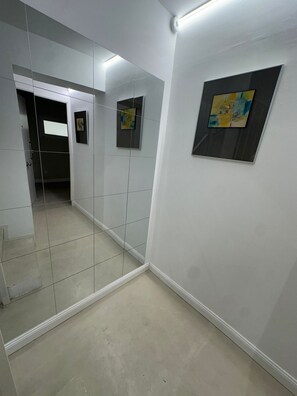 A hallway with a mirrored wall, a door leading to another room, and a framed picture on the wall. - Sol Mediterraneo - Palm City 2 (Elx/Elche)