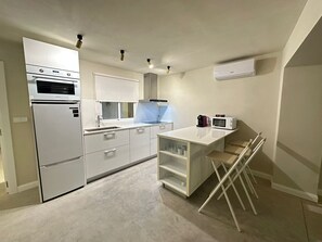 A modern kitchen with a built-in oven, microwave, and a window with blinds.