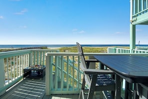 Um terraço com vista para a praia, uma mesa e uma cadeira.