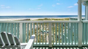 Eine Holzterrasse mit Blick auf den Strand und den Ozean.