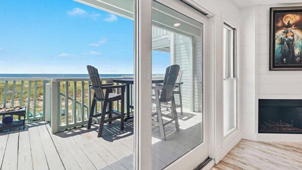 Ein Balkon mit Meerblick, einem Tisch mit Stühlen und einem Kamin.
