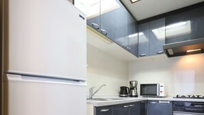 Een keuken met een koelkast, magnetron, koffiezetapparaat en fornuis.