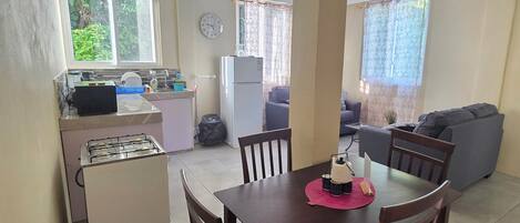 Un espacio habitable compacto con kitchenette, comedor y zona de estar.